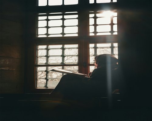 Woman reading a book by the window with natural soft sunlight